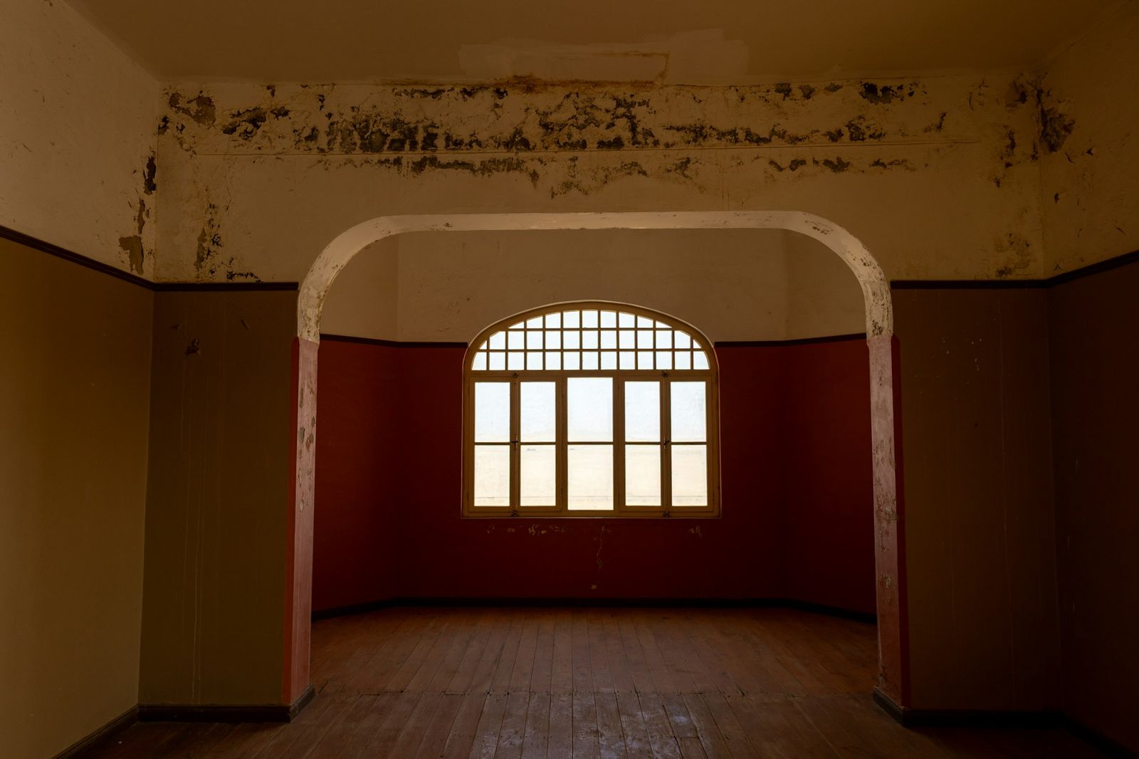 Leerer Altbauraum mit Rundbogenfenster