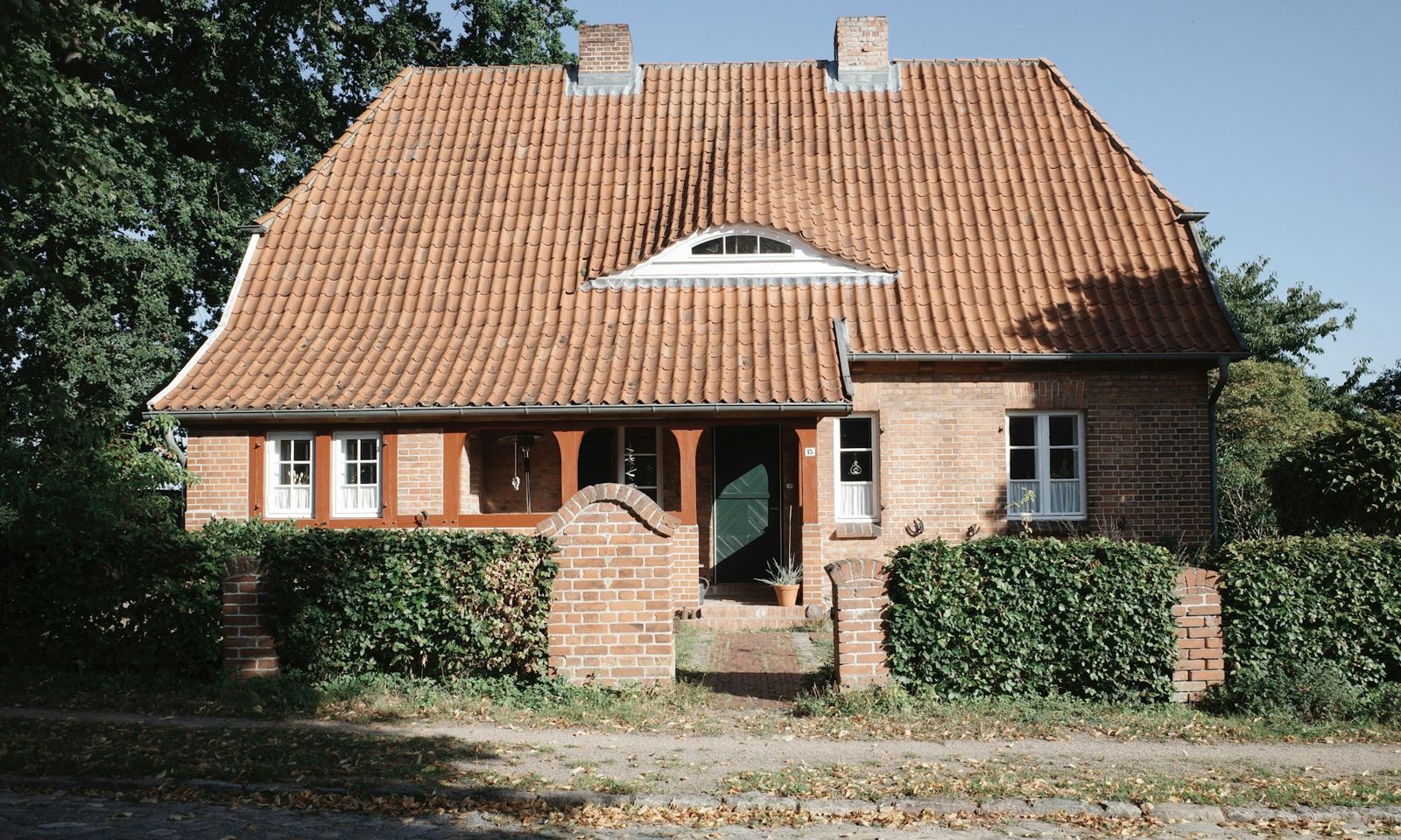 Freistehendes Einfamilienhaus in Klinkerbauweise mit Ziegeldach und Hecke
