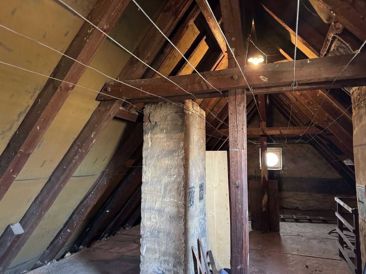 Dachstuhl mit Holzbalken und gemauertem Kamin